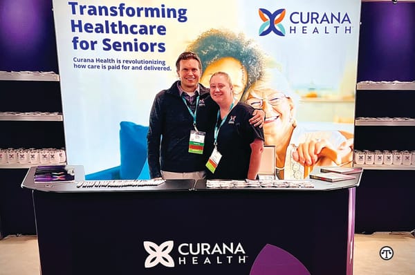 Two Curana Health employees in front of a trade booth