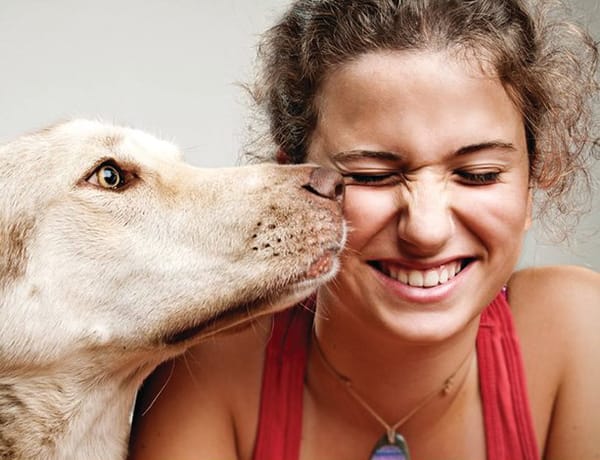 A woman with a dog kissing her nose.