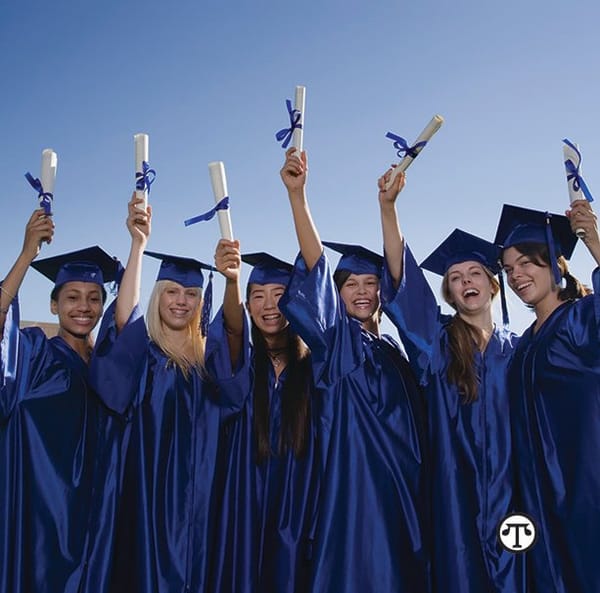 A group of women in graduation gowns holding up their diplomas.