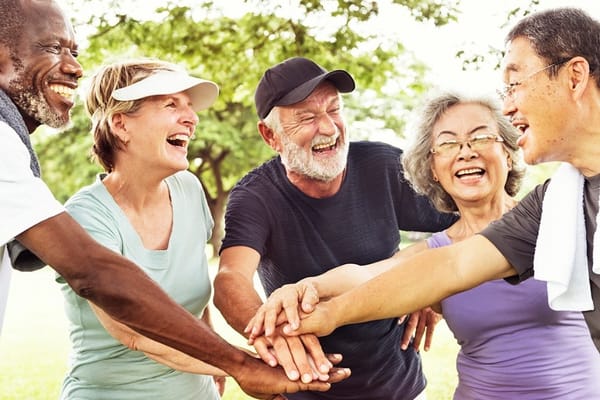 A group of older people holding hands in a park.