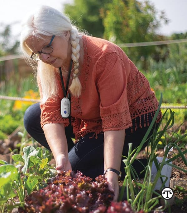 A woman kneeling down in a garden with a gps device.