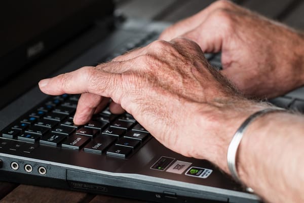 A man's hand typing on a laptop keyboard.