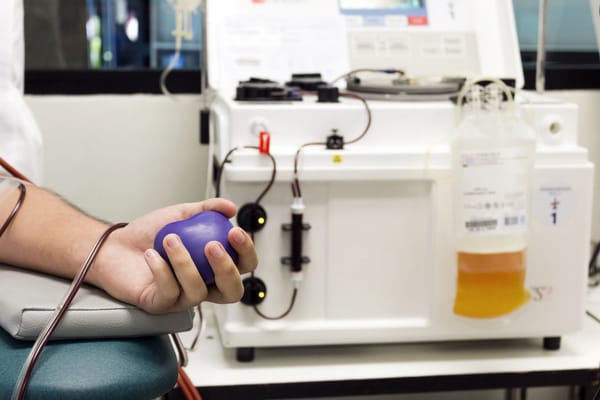 A man is holding a blue ball in front of a machine.