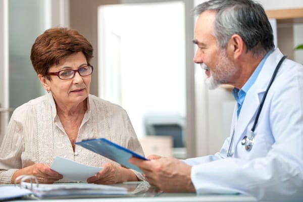 A doctor is talking to an older woman in a doctor's office.