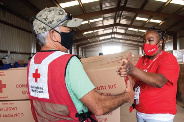 A man in a red cross vest and a woman in a red cross vest.