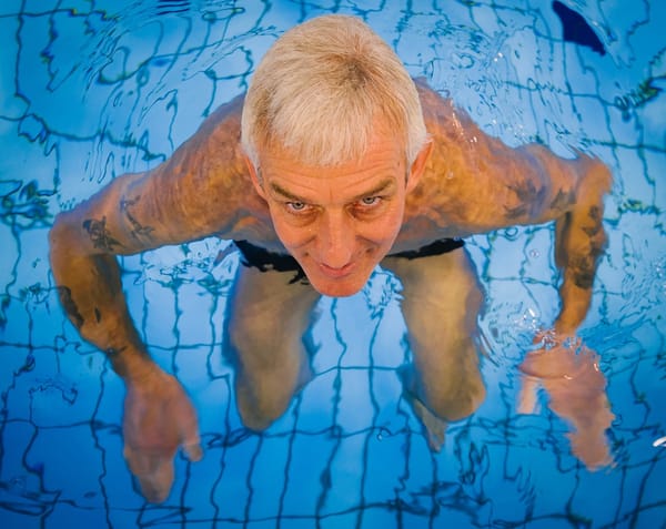 An older man swimming in a pool.