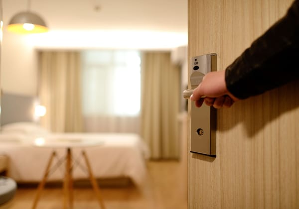 A person holding a door handle in a hotel room.