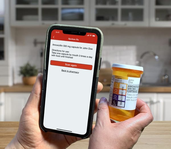 A person holding a smartphone with a prescription bottle in front of it.